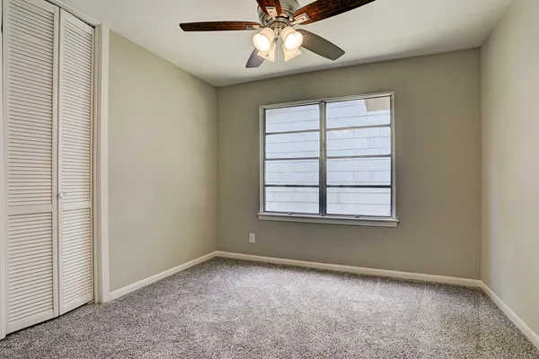 an empty room with a window and a fan