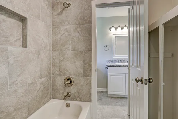 a bathroom with a tub a sink and mirror
