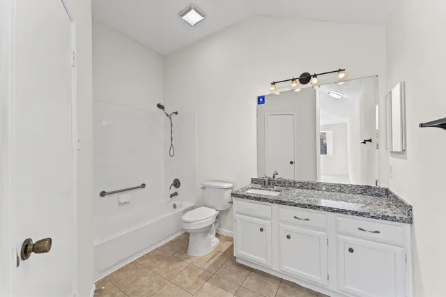 a bathroom with a granite countertop sink a toilet and shower