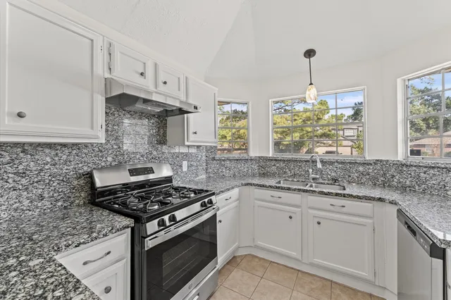 a kitchen with white cabinets appliances and a window