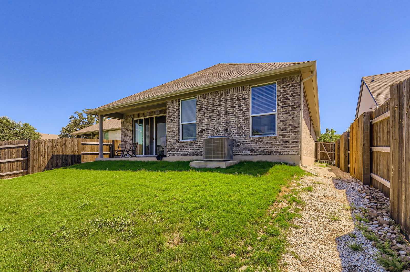 1909 Ruger Pass Leander, TX 78641 - Photo 27 of 31 Back of house with brick siding, a fenced backyard, and a shingled roof