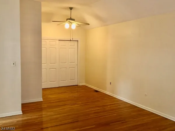 an empty room with wooden floor closet and fan