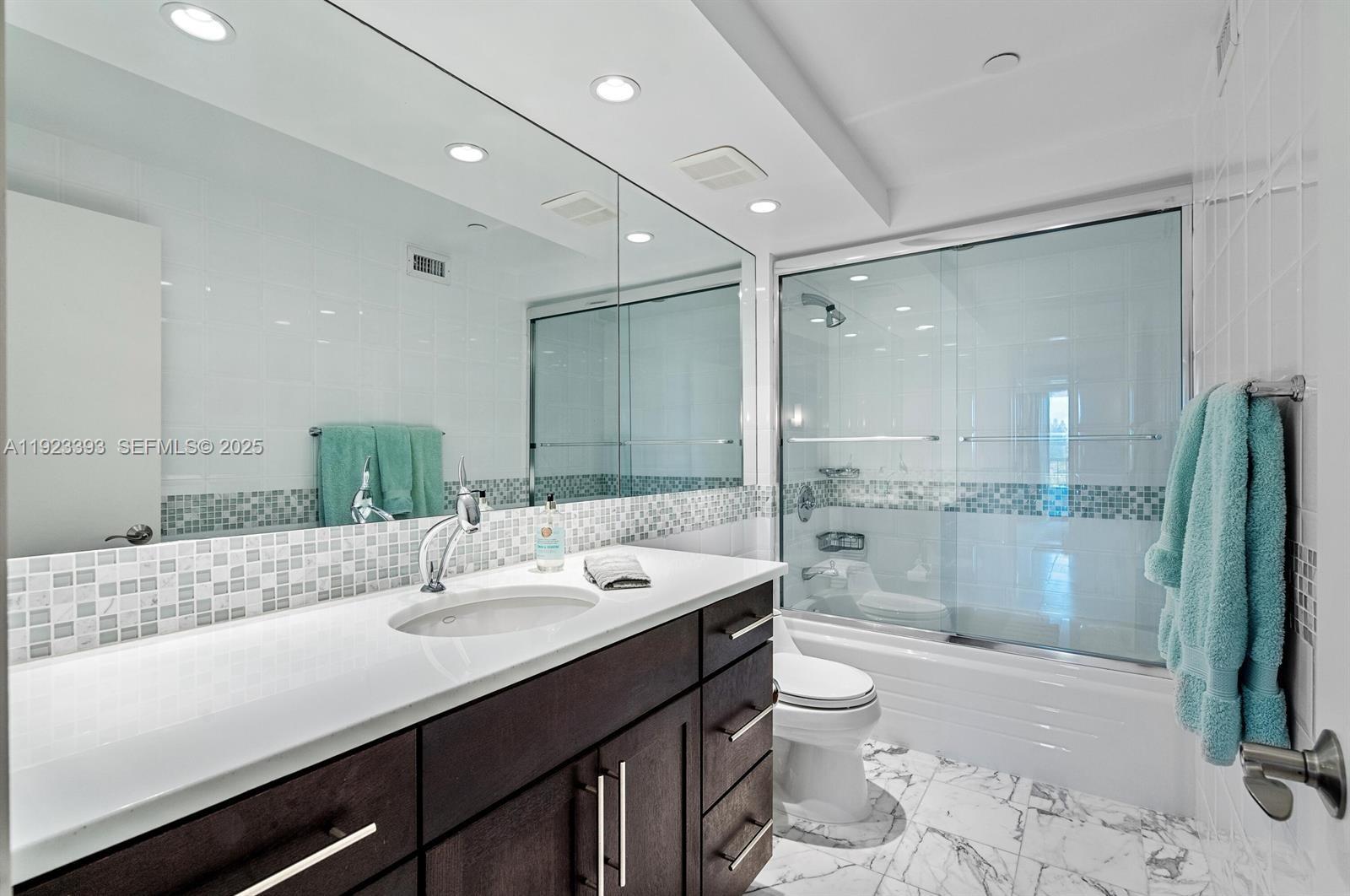 1800 South Ocean Boulevard, Unit 5C Boca Raton, FL 33432 - Photo 17 of 98 a bathroom with a granite countertop sink a toilet a mirror and shower