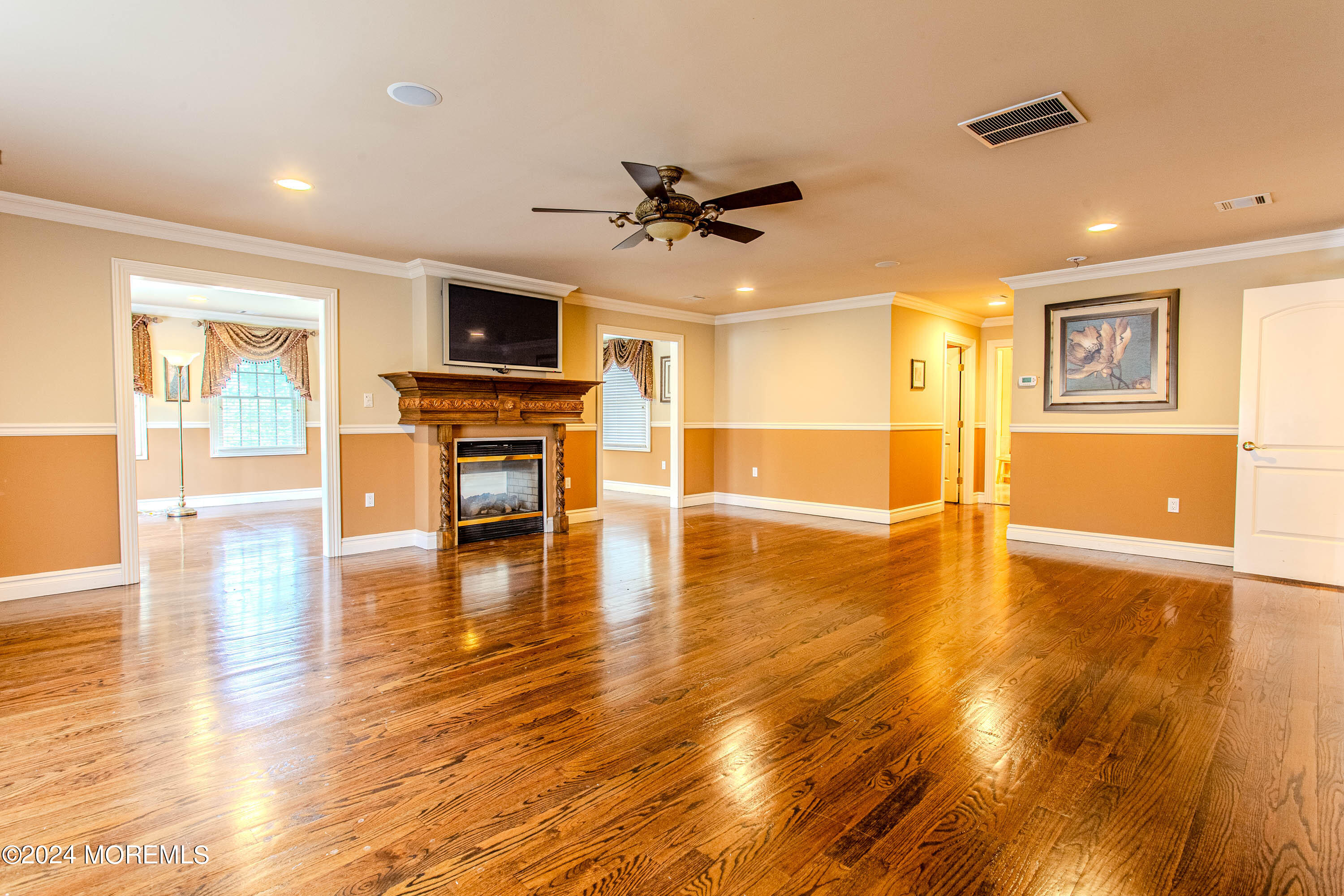 25 Woods End Road Colts Neck, NJ 07722 - Photo 33 of 76 a view of a livingroom with a flat screen tv wooden floor and a ceiling fan
