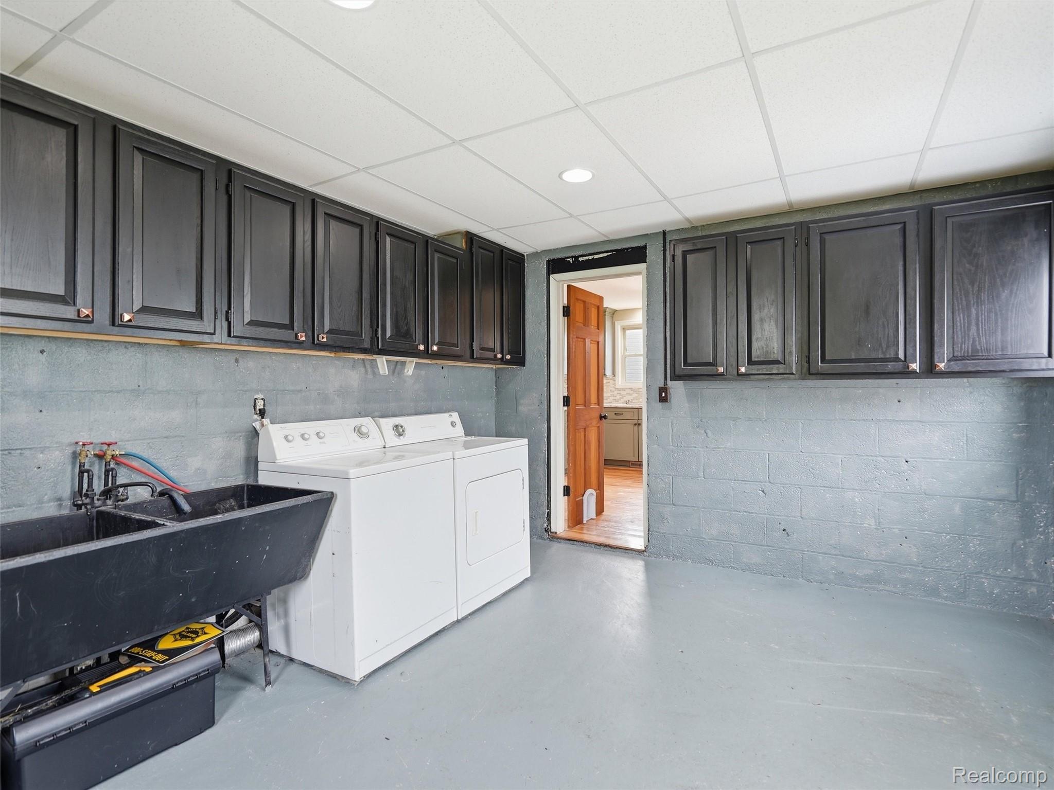 117 Kenyon Road Algonac, MI 48001 - Photo 24 of 47 Dedicated utility area featuring a double basin utility sink, extensive dark cabinetry, and neutral painted concrete block walls
