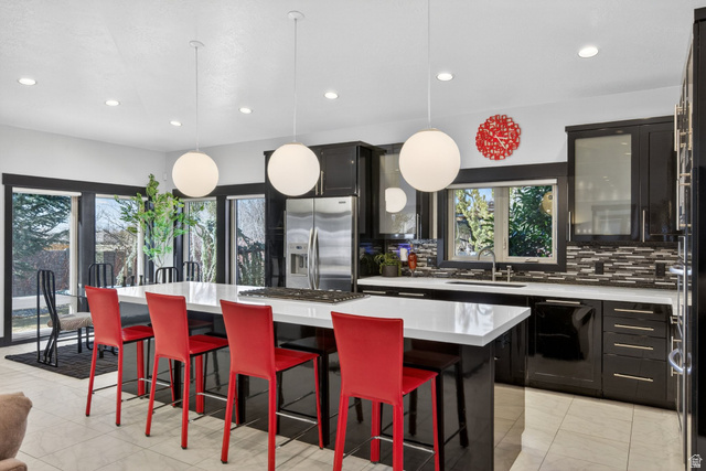 145 Carnesecca Court Mapleton, UT 84664 - Photo 24 of 109 Kitchen with a kitchen bar, a kitchen island, dark cabinets, stainless steel appliances, and backsplash