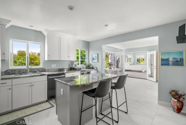 a kitchen with stainless steel appliances granite countertop a sink a stove a refrigerator cabinets and dining table