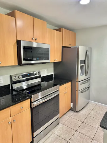a kitchen with granite countertop a refrigerator and a stove top oven