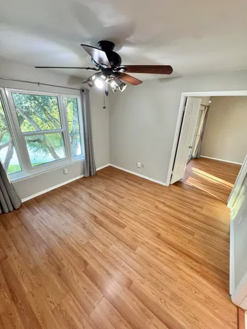 a view of empty room with wooden floor and fan