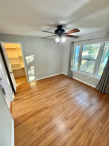 a view of empty room with wooden floor and fan