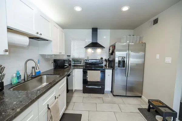 a kitchen with granite countertop a stove sink and refrigerator