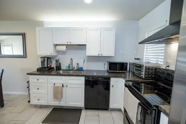a kitchen with granite countertop a stove sink and cabinets