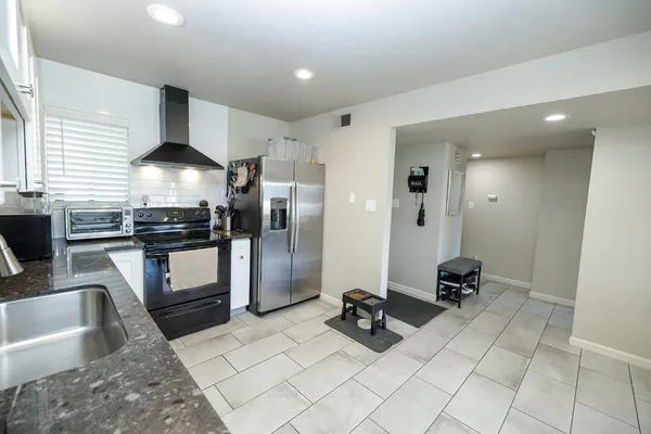 a kitchen with stainless steel appliances kitchen island granite countertop a refrigerator and a sink