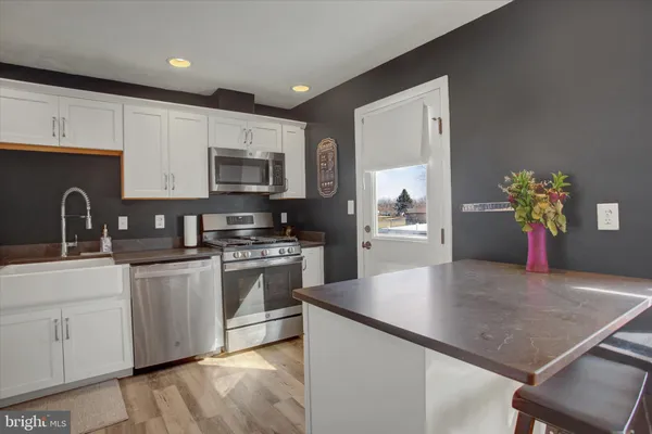 a kitchen with stainless steel appliances granite countertop a stove a sink a microwave and a refrigerator