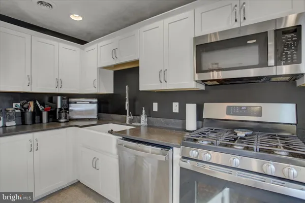 a kitchen with stainless steel appliances granite countertop a stove a sink and a microwave