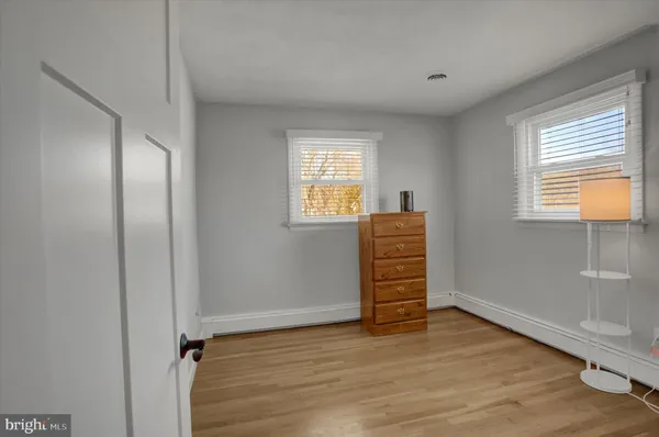 an empty room with wooden floor closet and windows