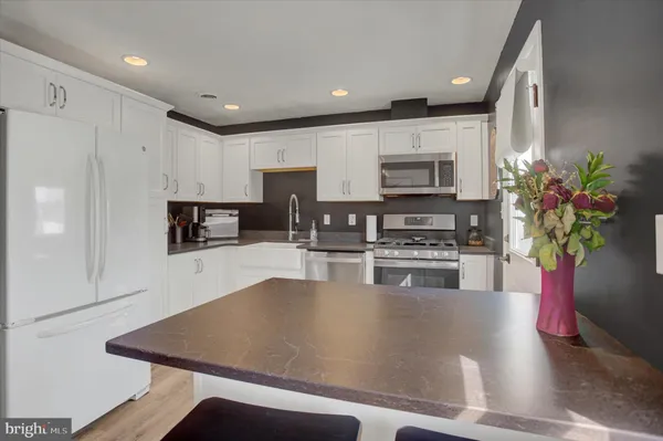 a kitchen with kitchen island a stove top oven a sink a counter top space and cabinets