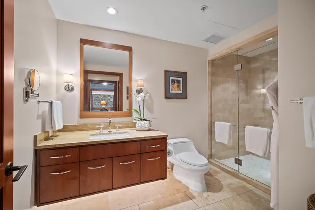a spacious bathroom with a granite countertop sink toilet a mirror and shower