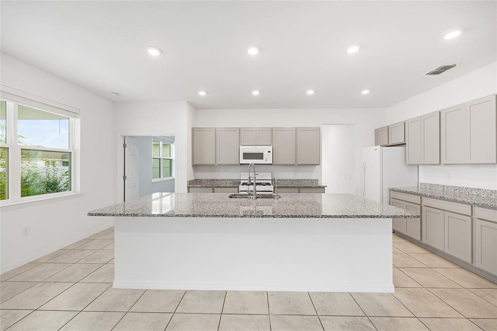 7635 Southwest 64th St Road Ocala, FL 34474 - Photo 15 of 86 a large kitchen with granite countertop a sink and white cabinets
