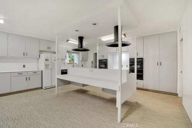 a large white kitchen with white cabinets and wooden floor
