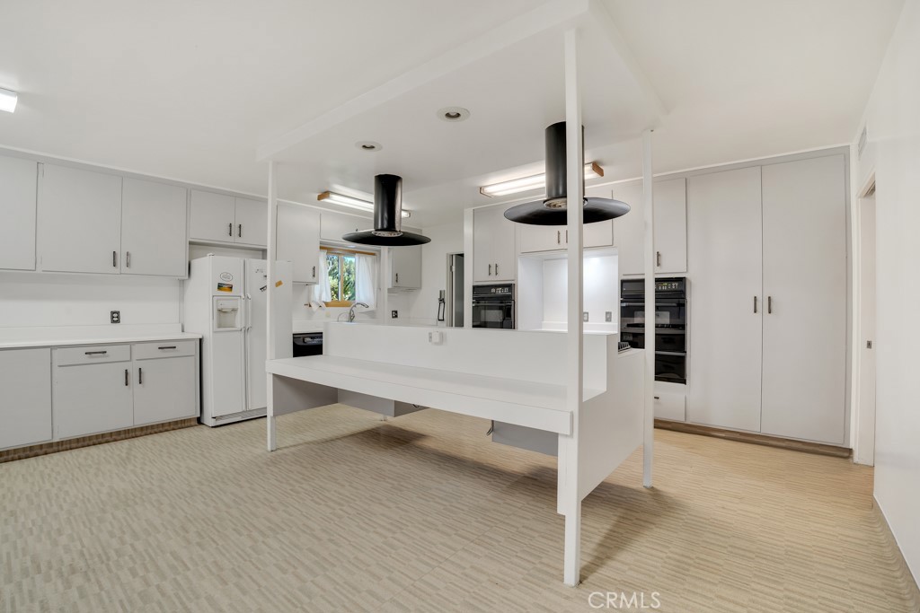 18912 Blackhawk Street Porter Ranch, CA 91326 - Photo 9 of 48 a large white kitchen with white cabinets and wooden floor