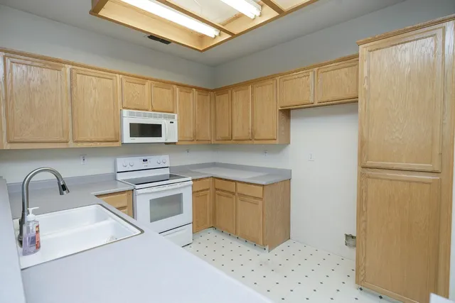 a kitchen with stainless steel appliances granite countertop a sink a stove a refrigerator with grey cabinets