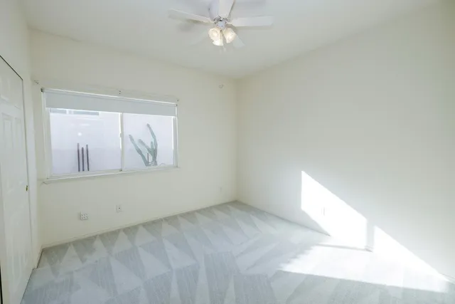 an empty room with windows and fan
