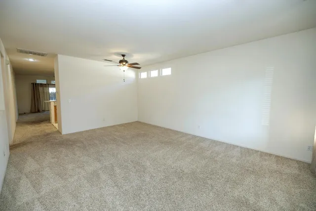 an empty room with a chandelier fan and windows