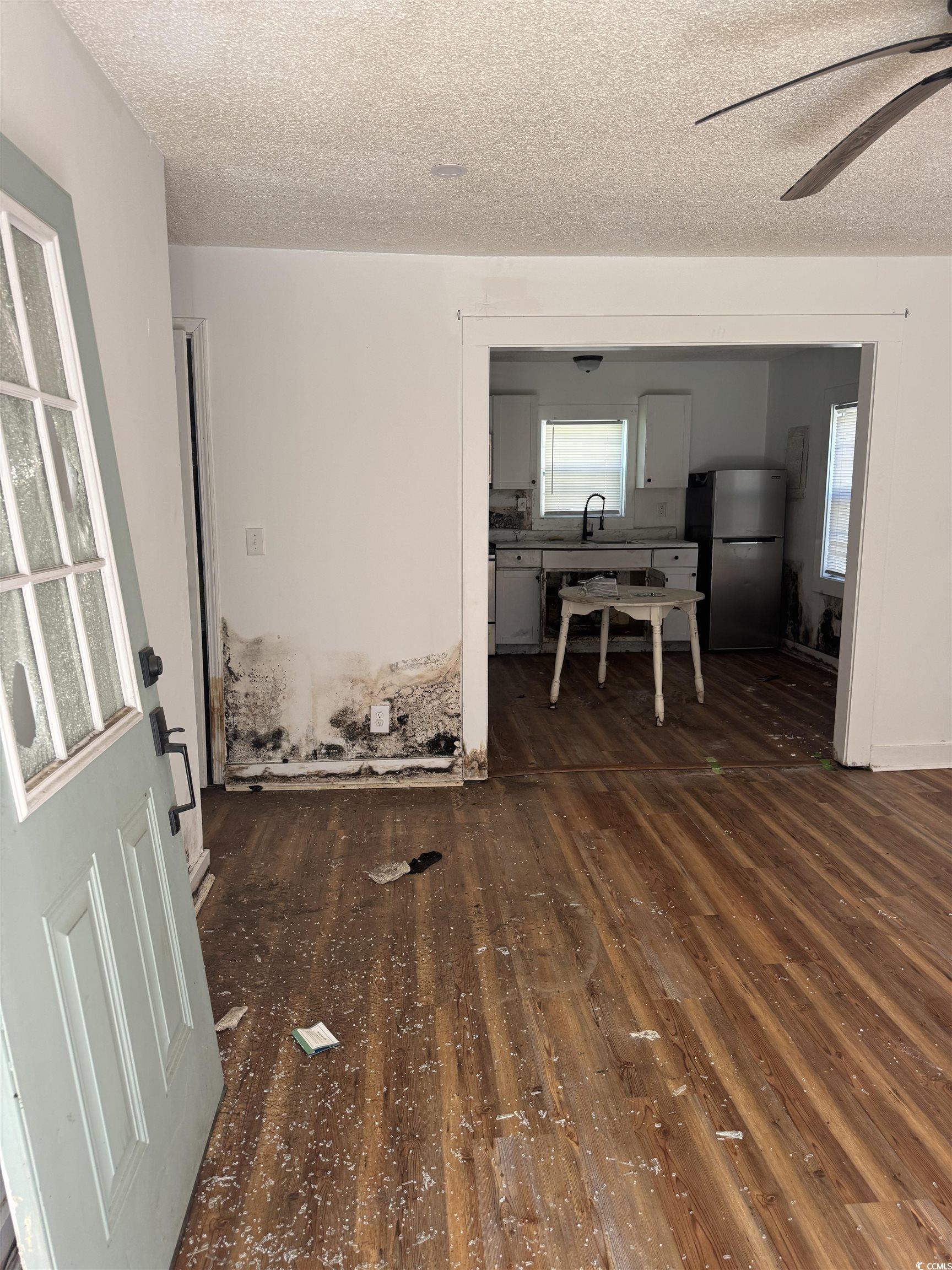 Living room featuring dark wood finished floors, a textured ceiling, and ceiling fan