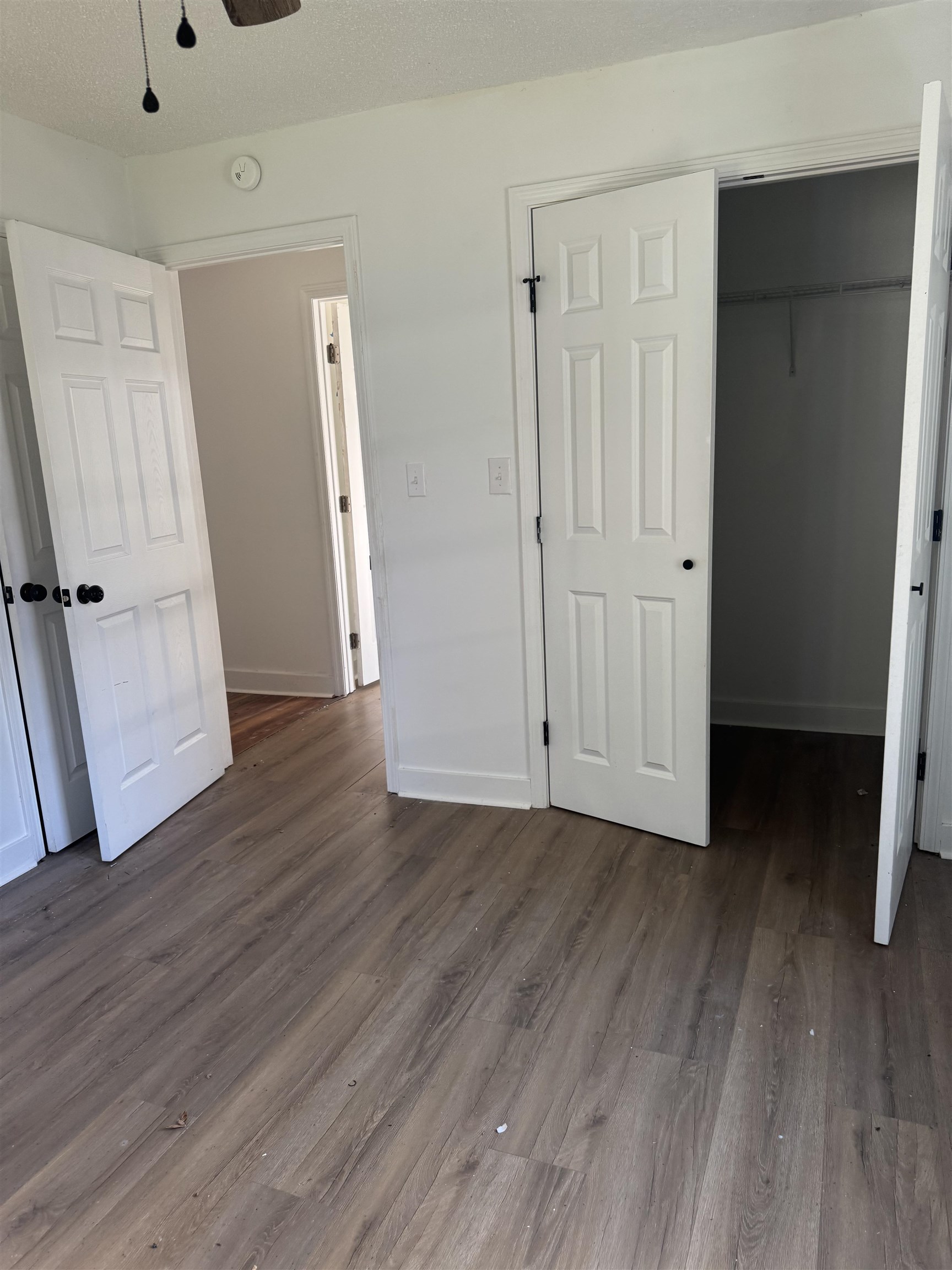 Unfurnished bedroom with dark wood-style floors, a textured ceiling, ceiling fan, and a walk in closet