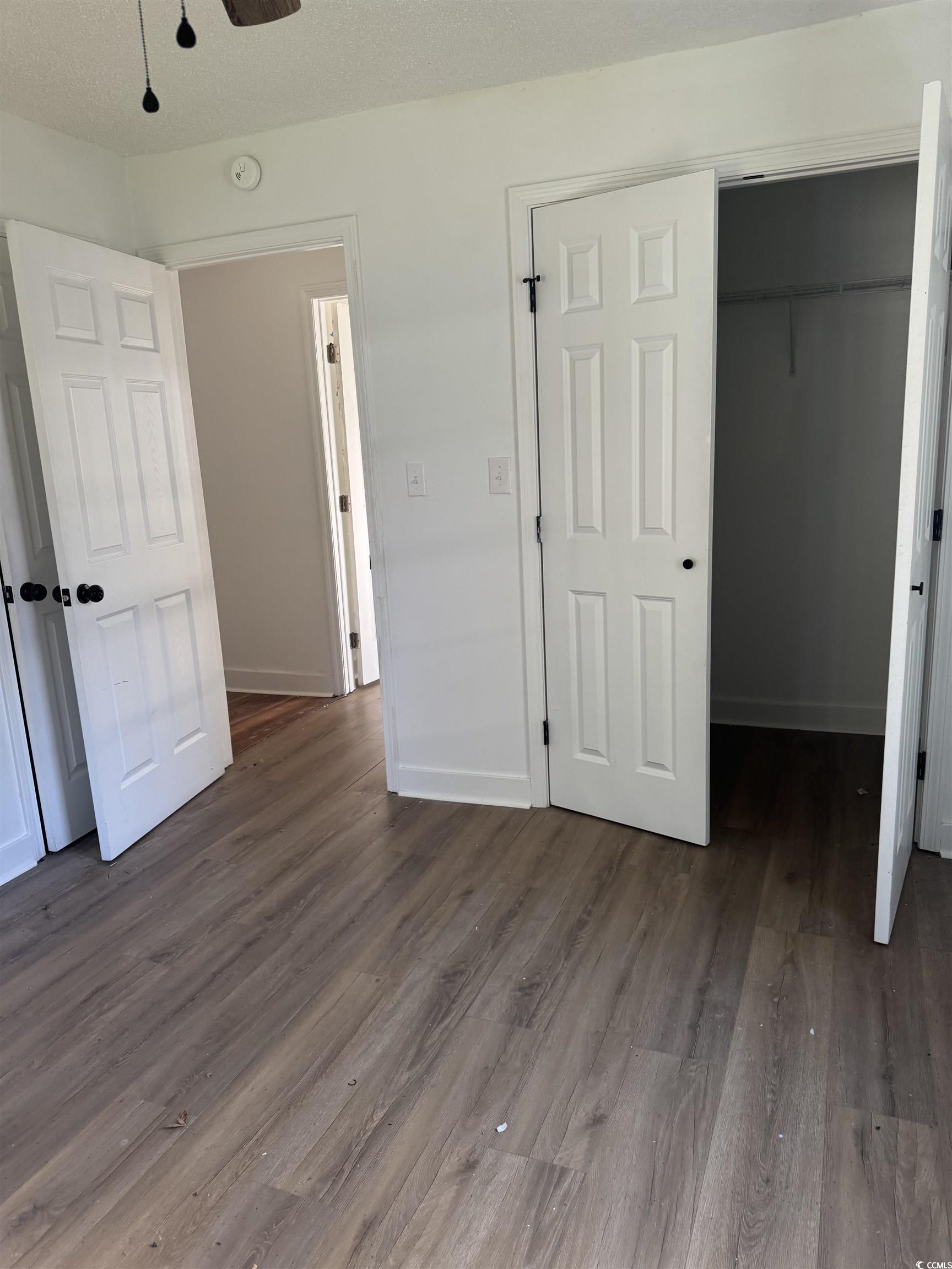 809 North Dargan Street Florence, SC 29506 - Photo 10 of 13 Unfurnished bedroom with dark wood finished floors, a textured ceiling, ceiling fan, and a walk in closet