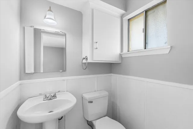 a bathroom with a toilet a sink and mirror