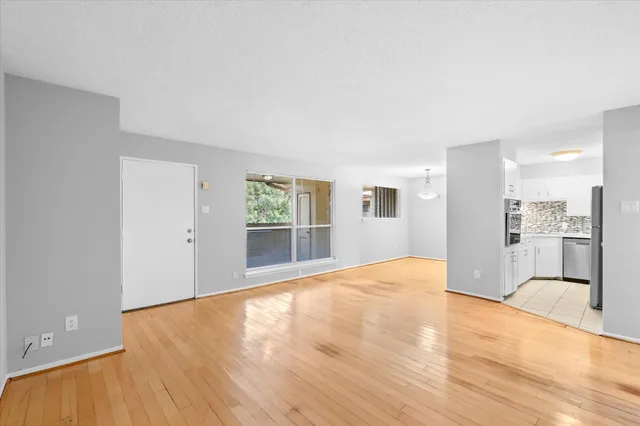 a view of empty room with wooden floor and a window
