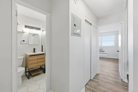 a view of a hallway with bathroom and wooden floor