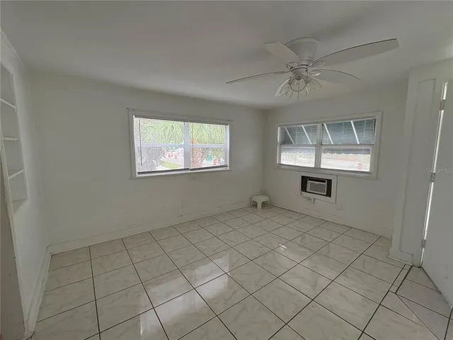 an empty room with windows and fan