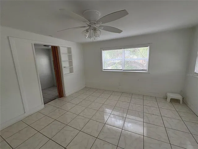 an empty room with fan and windows