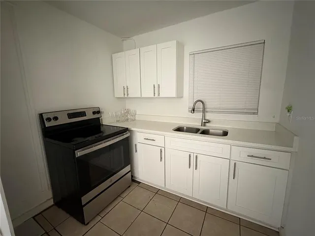a kitchen with white cabinets and appliances