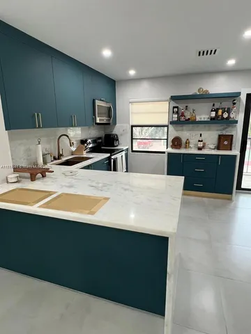 a kitchen with kitchen island sink cabinets and appliances
