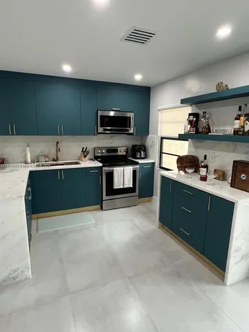 a kitchen with stainless steel appliances granite countertop a sink and a stove top oven