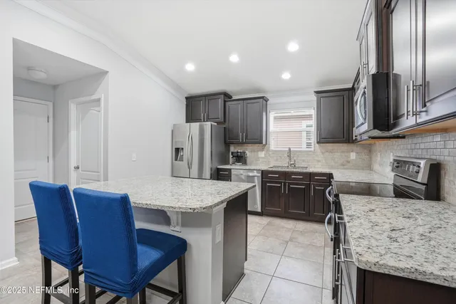 a kitchen with stainless steel appliances granite countertop a stove a sink a microwave a dining table and chairs