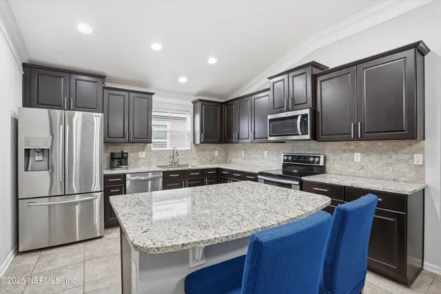 a kitchen with granite countertop a refrigerator a sink a stove a microwave and wooden cabinets
