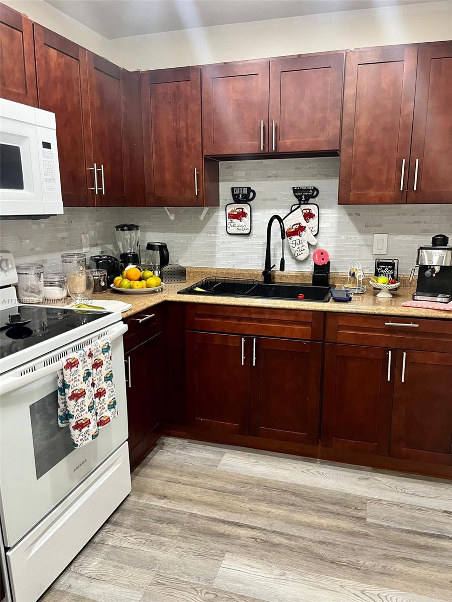 500 Davis Road, Unit 30 Palm Springs, FL 33461 - Photo 5 of 15 a kitchen with stainless steel appliances wooden cabinets and a stove top oven
