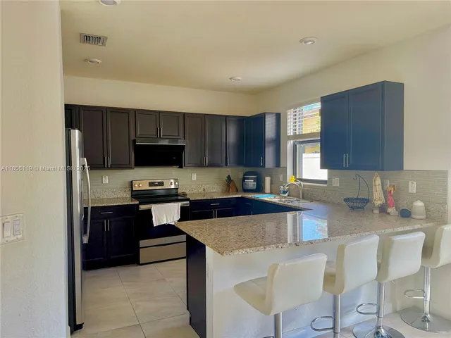 a kitchen with granite countertop a stove top oven a sink dishwasher and cabinets with wooden floor