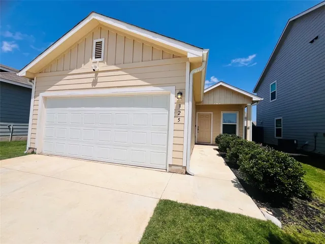 a view of house with garage and plants