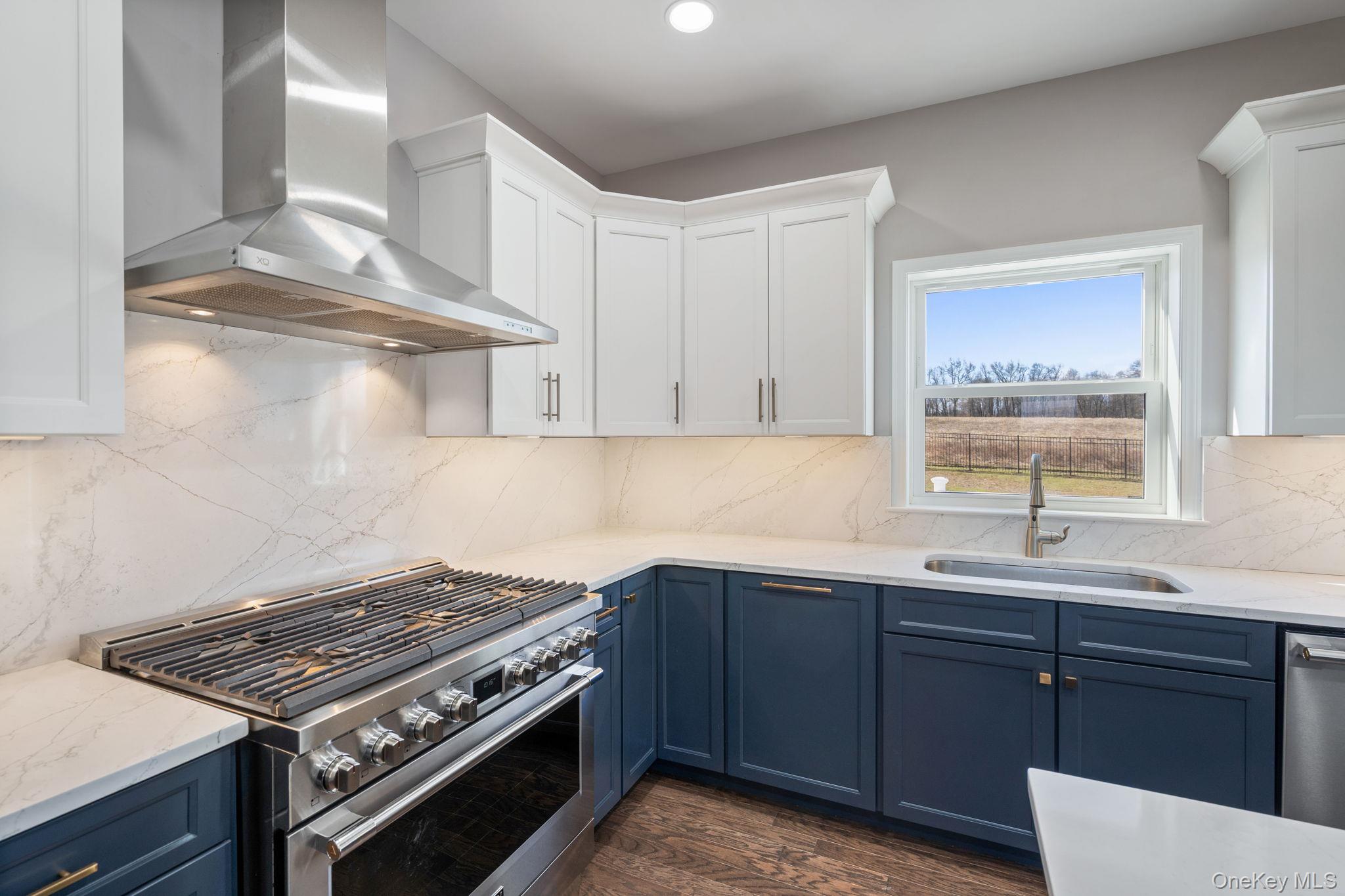 10 Harrier Ridge Drive Wallkill, NY 12589 - Photo 6 of 46 Kitchen featuring appliances with stainless steel finishes, wall chimney exhaust hood, light stone countertops, white cabinets, and blue cabinetry