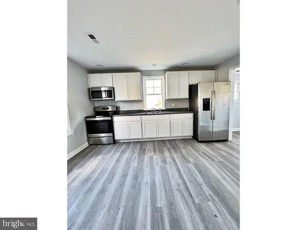 a large white kitchen with sink and stainless steel appliances