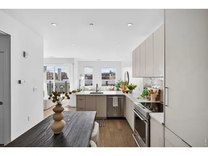 a kitchen with stainless steel appliances a refrigerator a sink dishwasher with a dining table and chairs