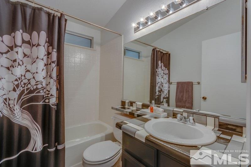 6006 White Water Way Reno, NV 89523 - Photo 16 of 20 a bathroom with a double vanity sink toilet mirror and shower