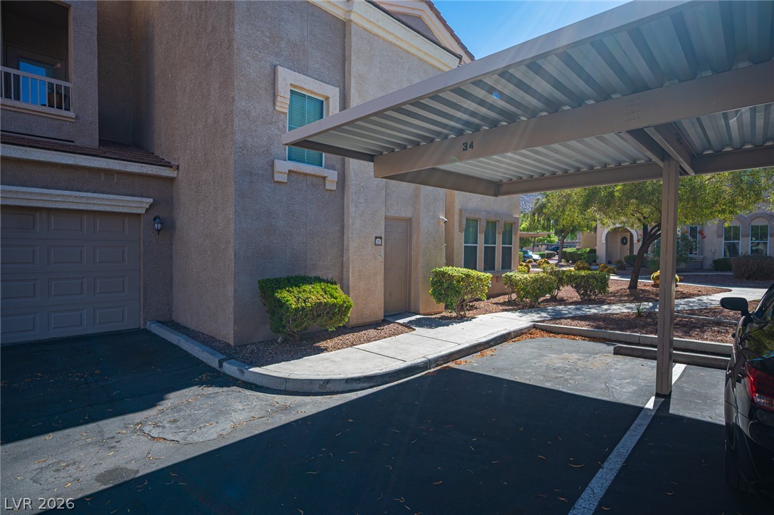10550 West Alexander Road, Unit 2014 Las Vegas, NV 89129 - Photo 40 of 43 Covered parking stands adjacent to the stucco exterior of this multi-level residential building.