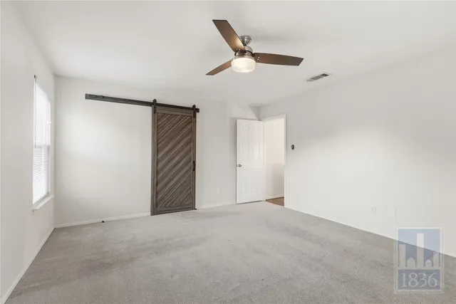 an empty room with ceiling fan and window